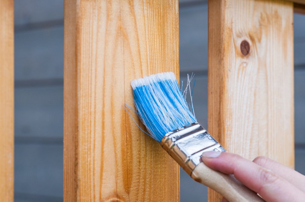 painting a garden fence with blue pain